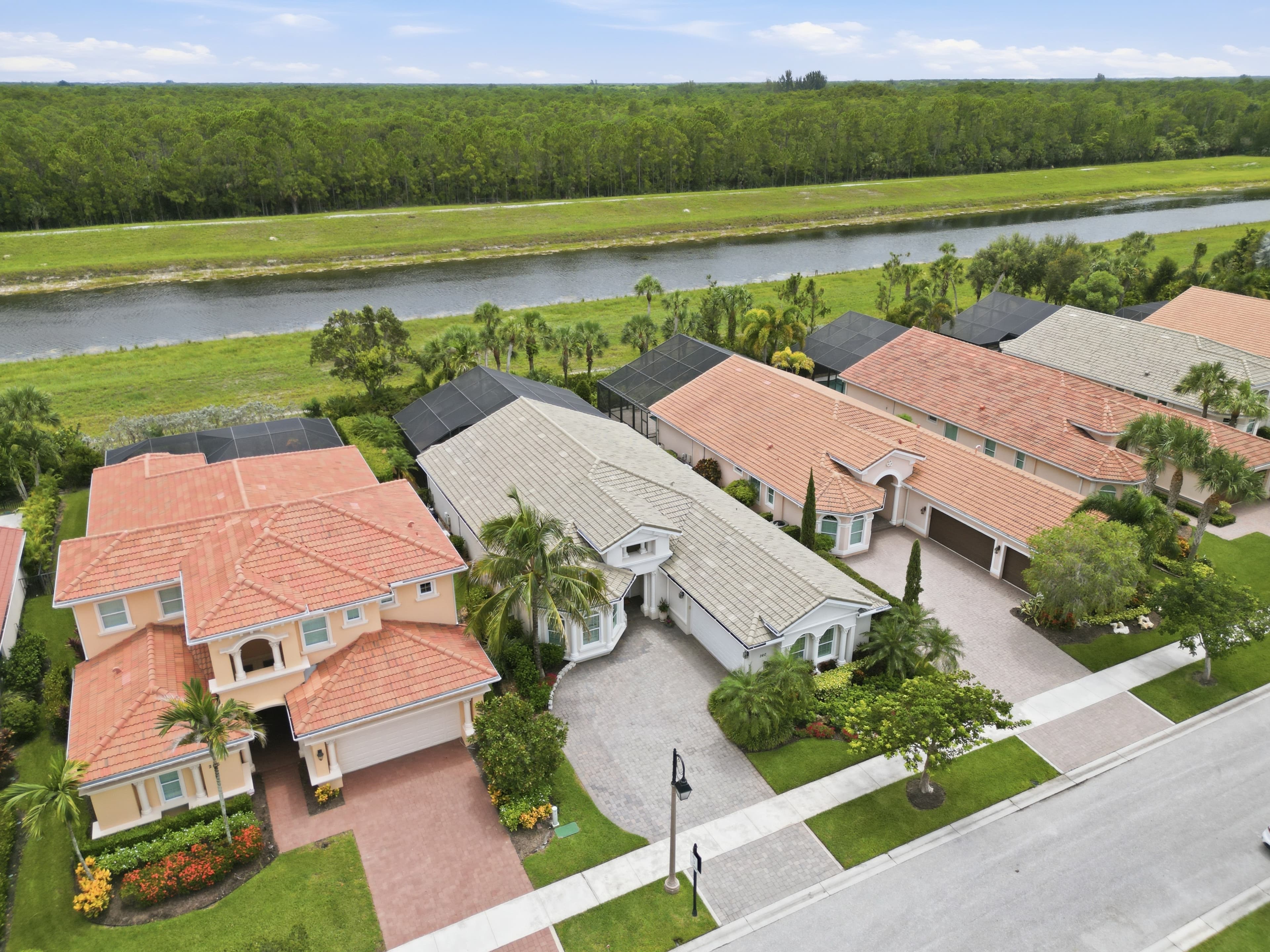 Aerial of canal-front homes with tile roofs and screened pool cages