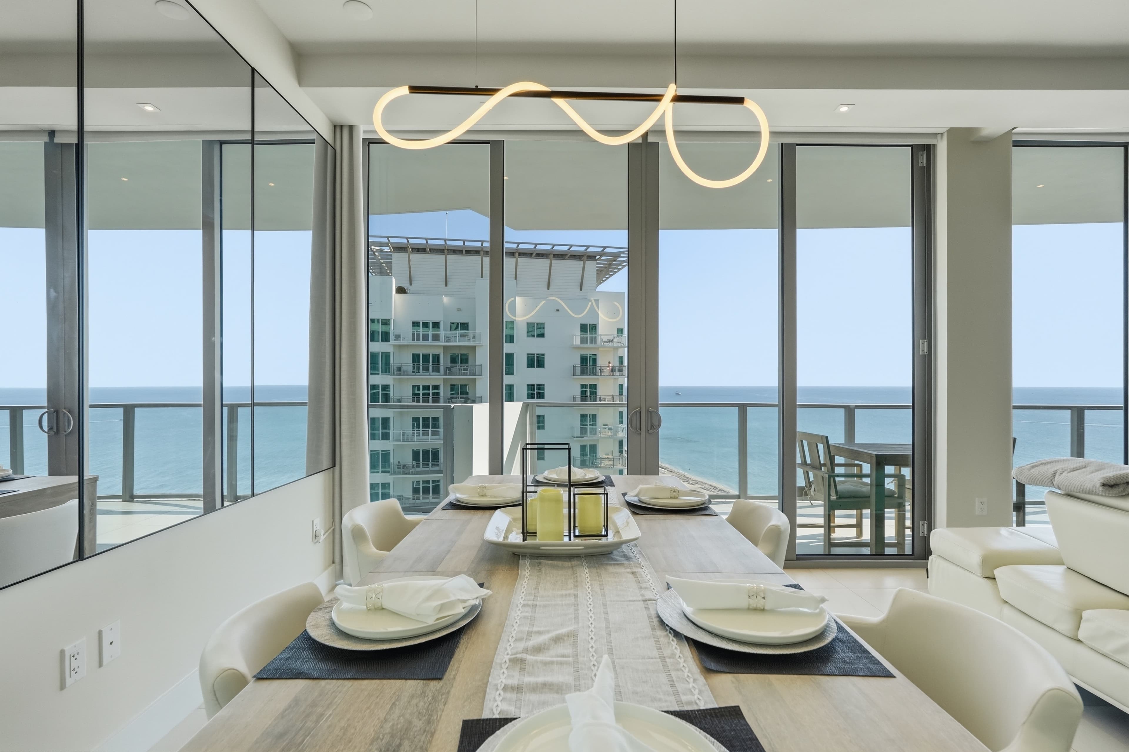 Dining table by floor-to-ceiling windows overlooking the ocean