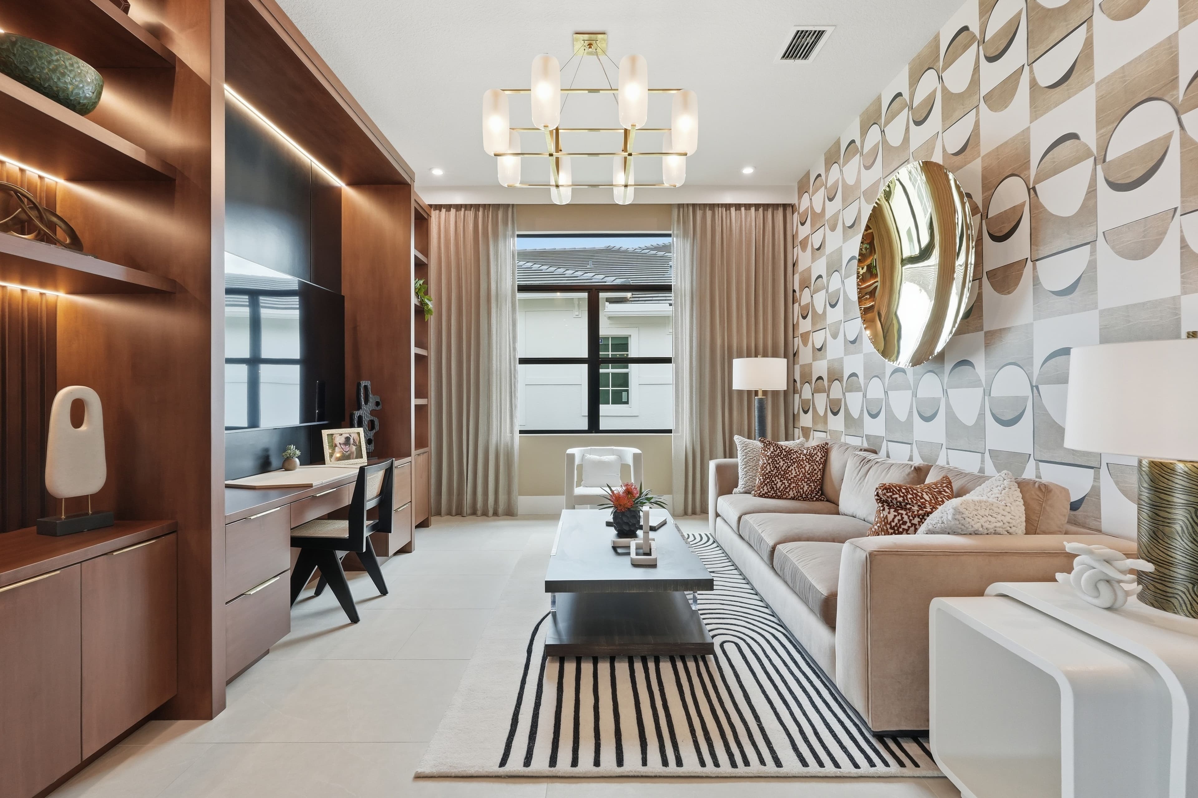Den with wood built-ins, tan sofa, and geometric wallpaper